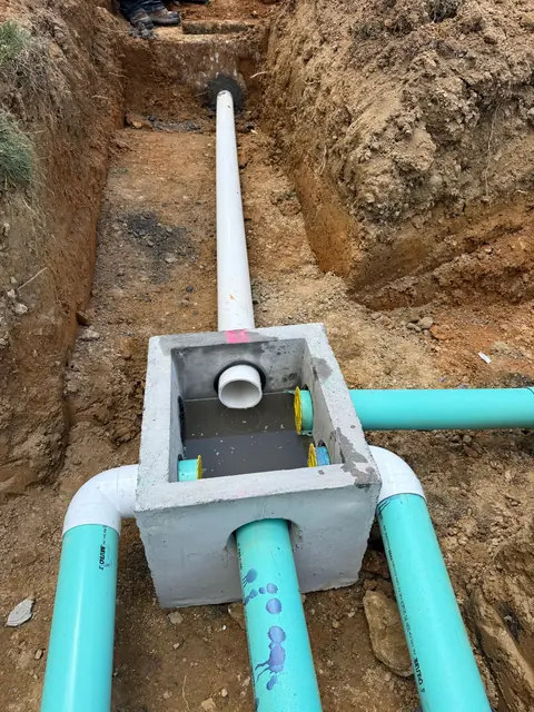 Concrete distribution box set in a trench with sealed pipe connections.
